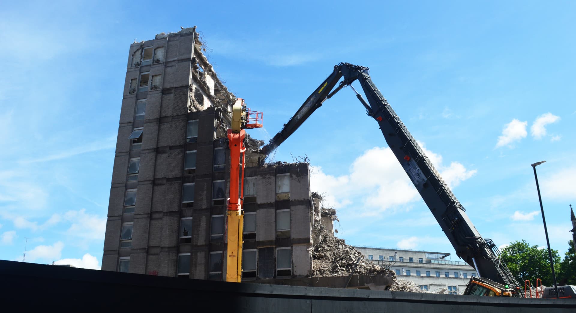 High-reach demolition machine making safe a partially collapsed multi-storey building on an emergency call-out